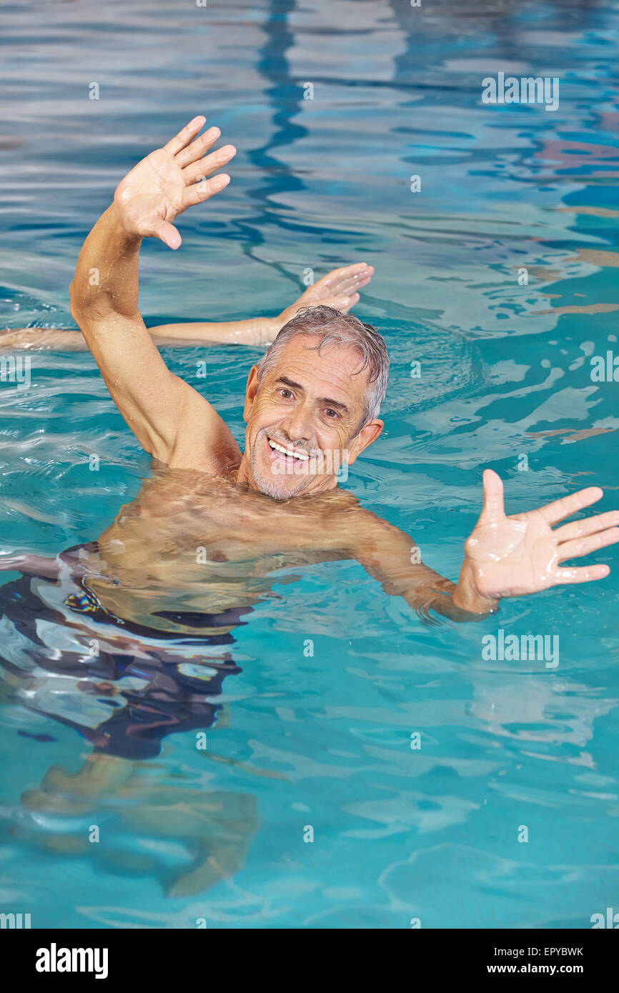 Ältere Menschen spielen Wasserball im Pool mit seinen Händen zu erreichen Stockfoto