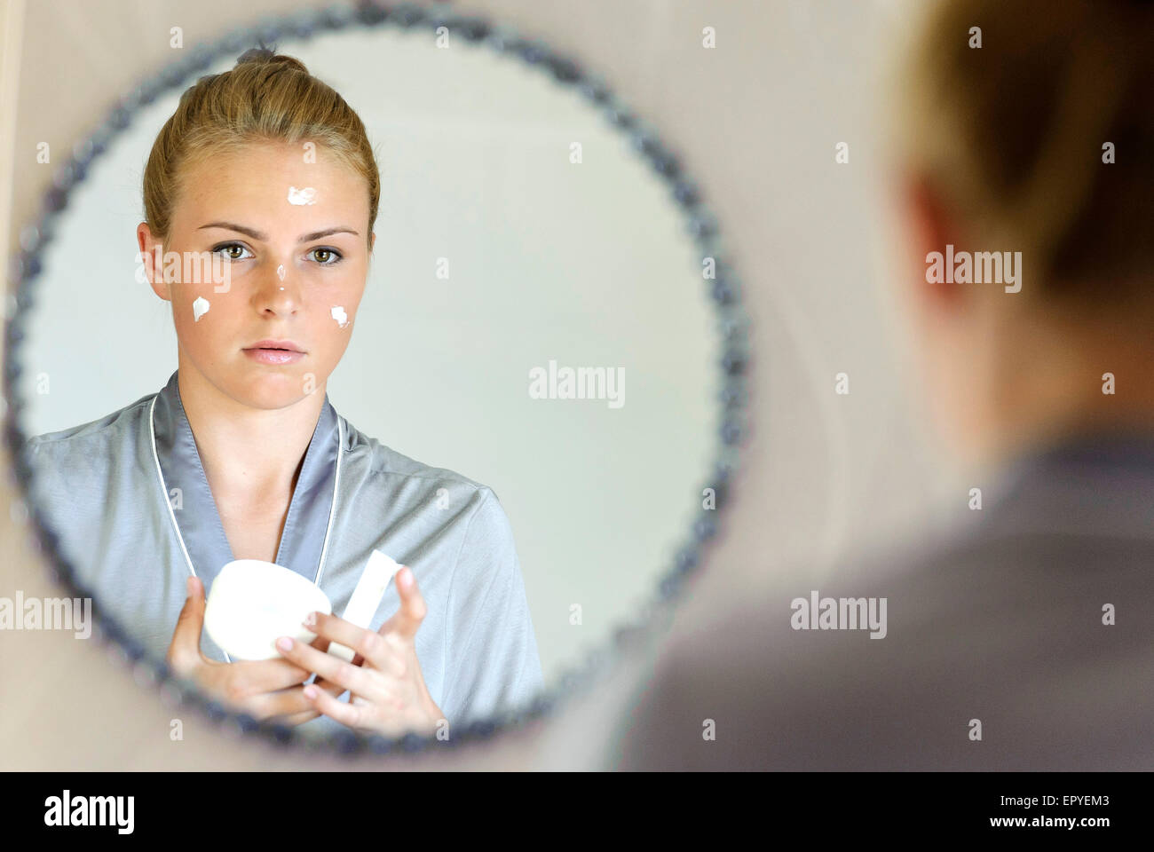 Schöne junge Frau, die Anwendung der Gesichtscreme Stockfoto