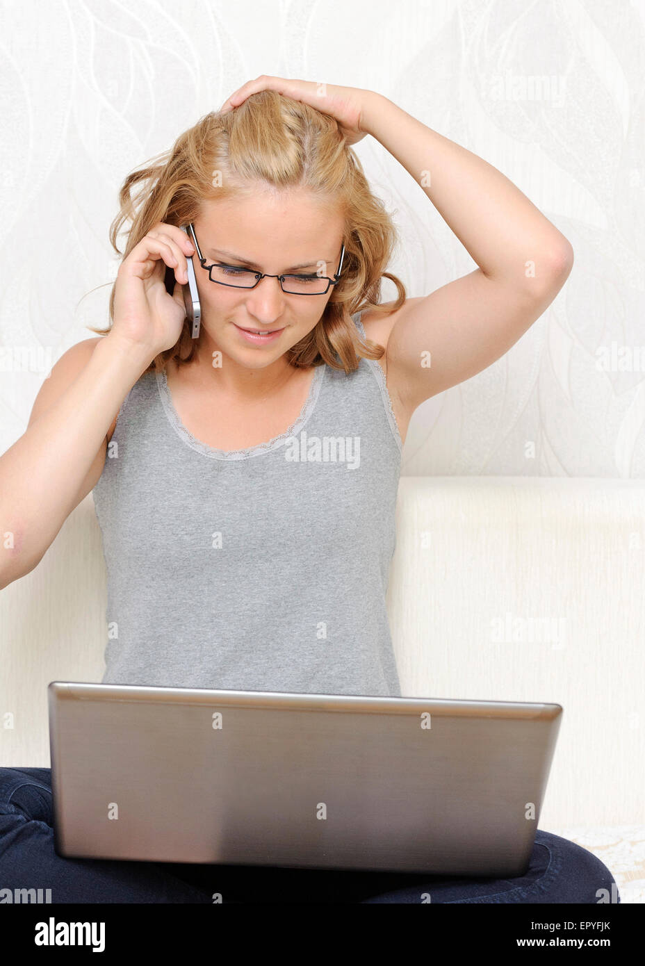 Junge Frau mit einem Laptop am Telefon sprechen Stockfoto