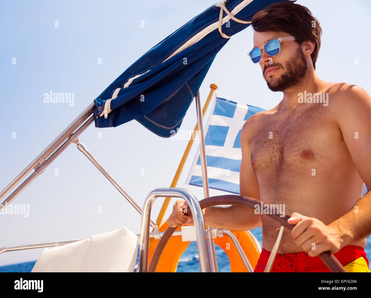 Gut aussehender Mann fahren Segelboot, aktiven Lebensstil, Spaß im Meer in hellen, sonnigen Tag, glücklich Sommerurlaub genießen Stockfoto