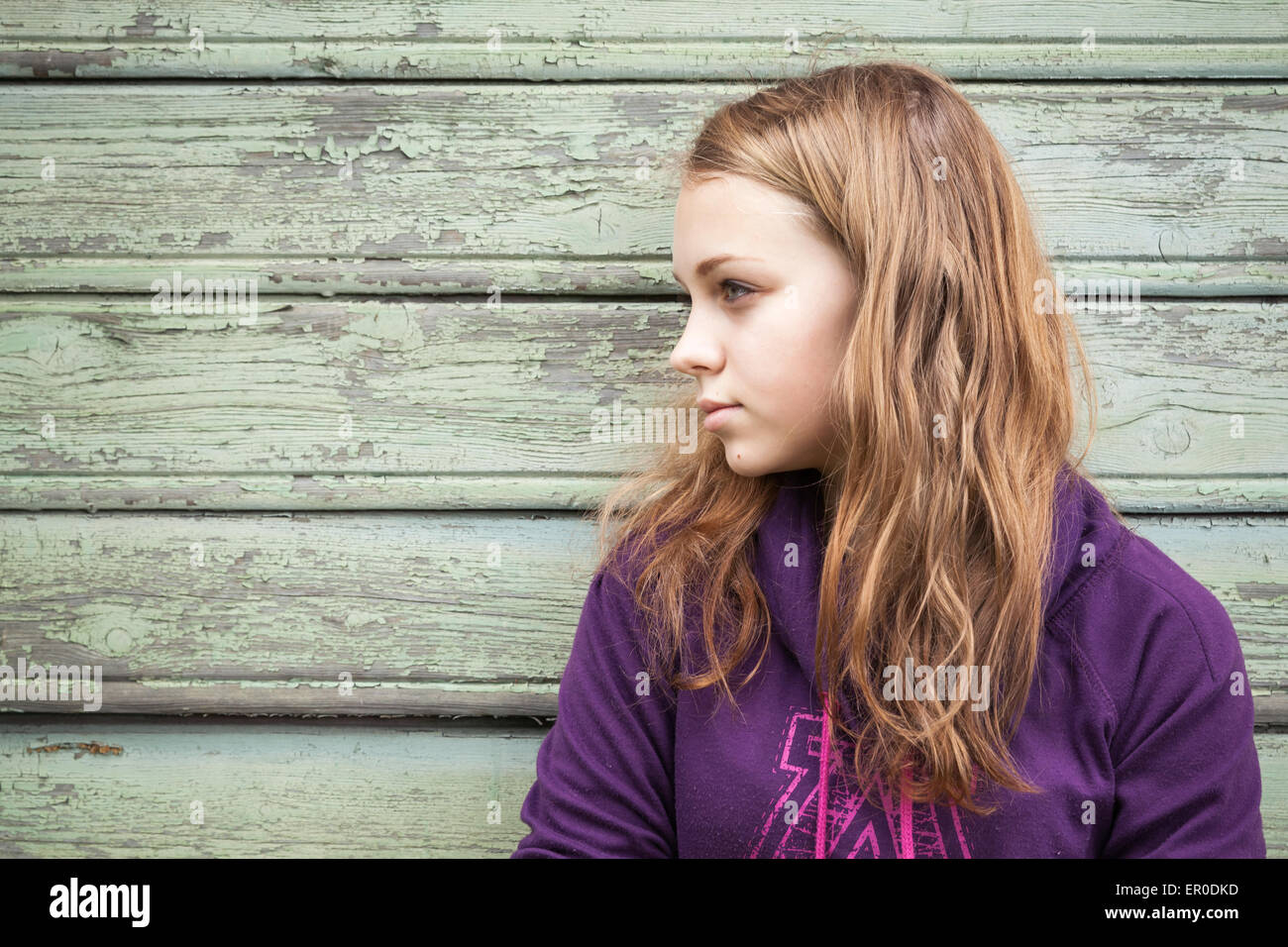 Schöne blonde kaukasische Mädchen Teenager, Nahaufnahme outdoor Profilbildnis über grüne Holzwand Stockfoto