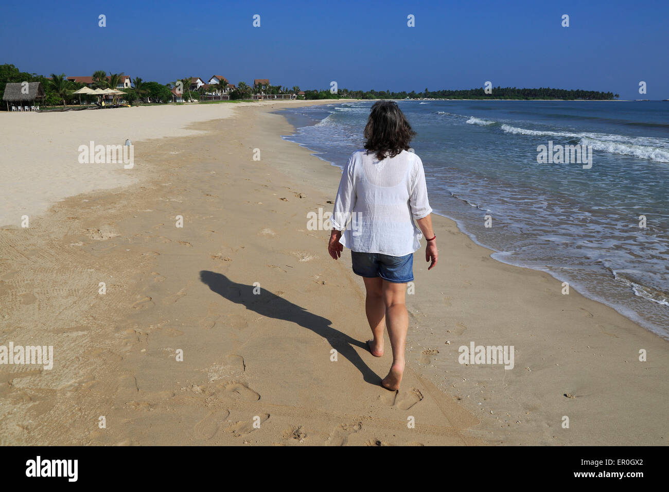 Ozean und Frau zu Fuß auf tropischen Sandstrand an der Bucht Pasikudah, Eastern Province, Sri Lanka, Asien Stockfoto