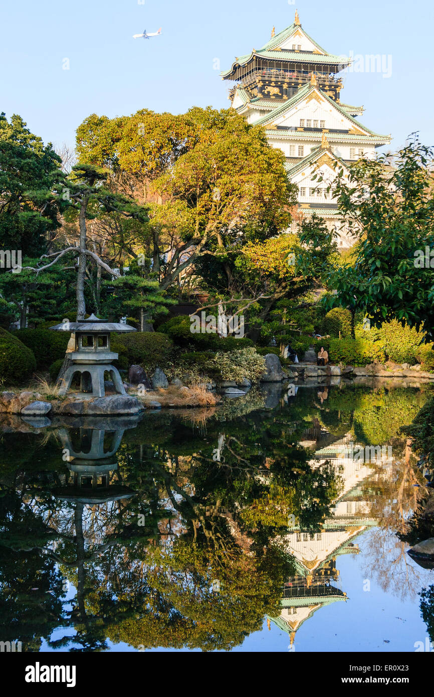 Osaka Castle Keep, im Borogata-Stil, ragt über dem japanischen Garten des Kishu Palace und spiegelt sich im Teich. Steinlaterne im Vordergrund. Stockfoto