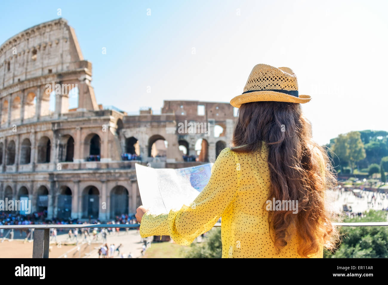 An heißen Sommertagen eine Frau von hinten gesehen und ist im Besitz einer Karte von Rom. Sie ist Blick auf Roms Kolosseum und die Stockfoto