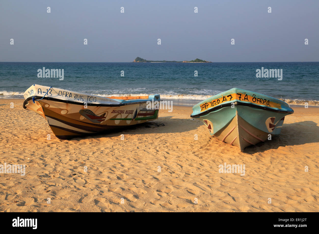 Boote am tropischen Strand von Nilavelli, Trincomalee, Sri Lanka, Asien mit Pigeon Island im Hintergrund Stockfoto