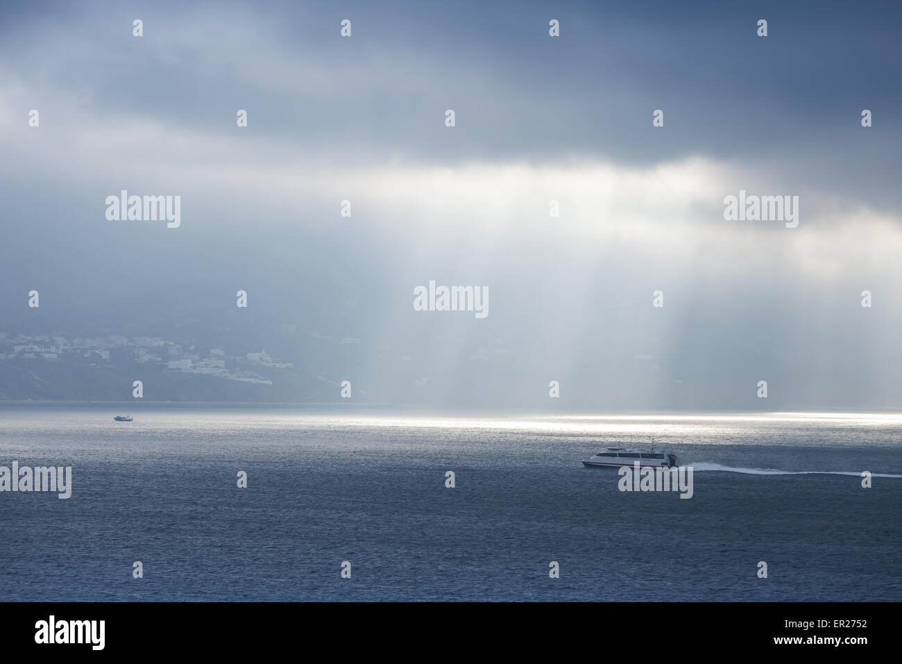 Volumen-Sonnenlicht geht durch dunkle blaue Wolken. Bucht von Tanger, Marokko, Afrika Stockfoto