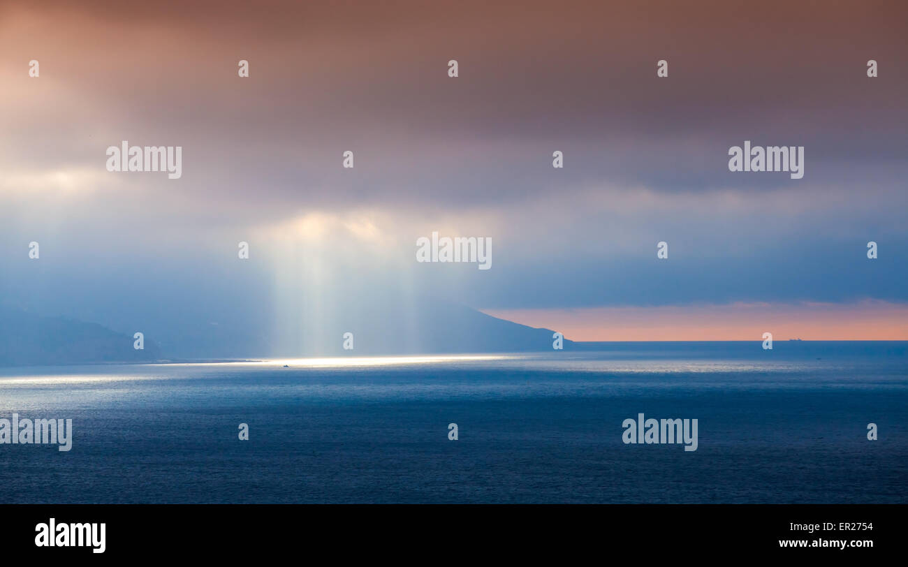 Volumen-Sonnenlicht geht durch dunkle Wolken. Bucht von Tanger, Marokko, Afrika Stockfoto