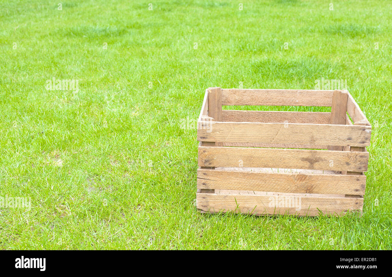Leere Holzkiste auf dem grünen Rasen, Platz für Text. Stockfoto