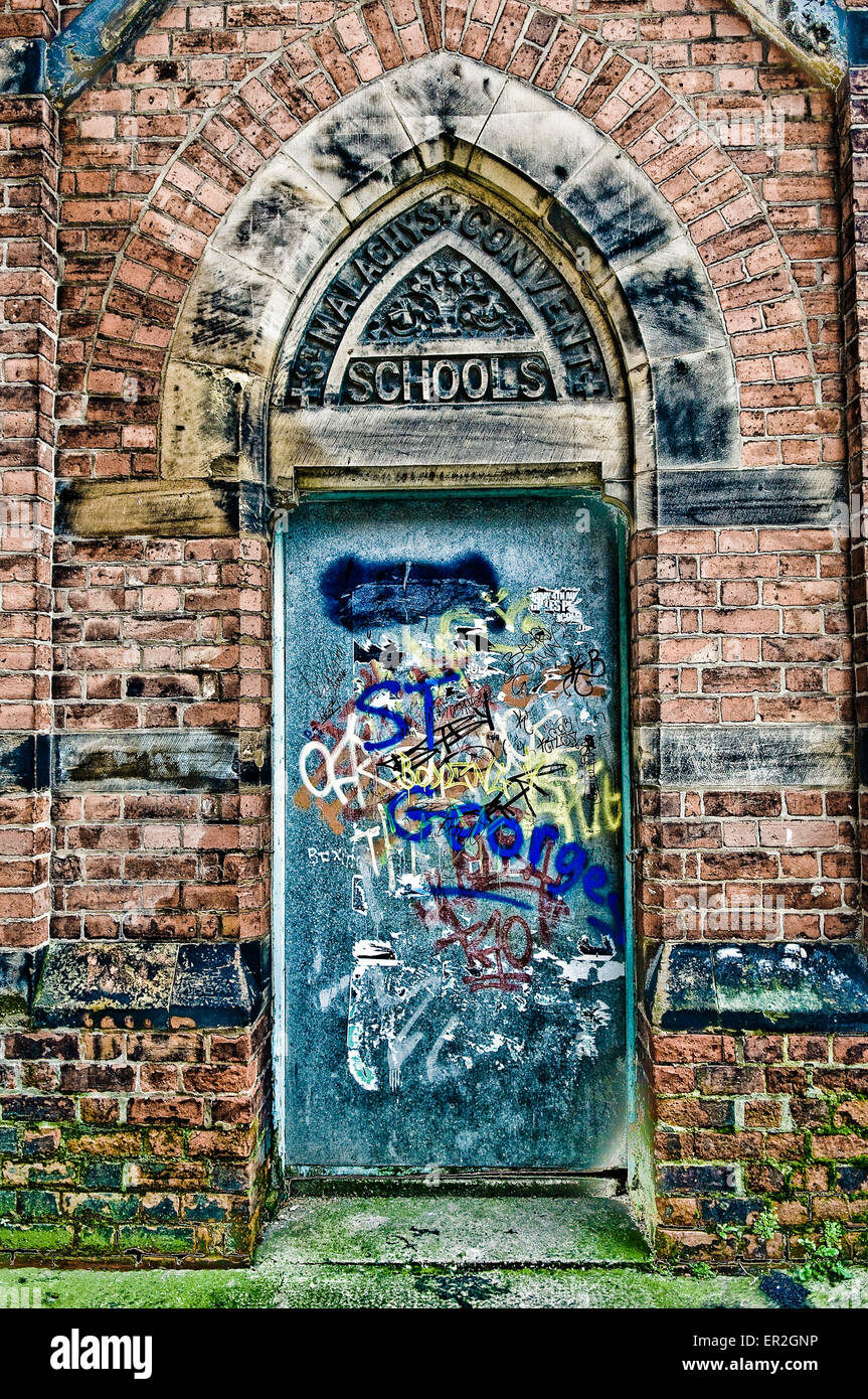 Eine alte, Metall Tür an einer Schule, mit Graffiti bedeckt. Stockfoto