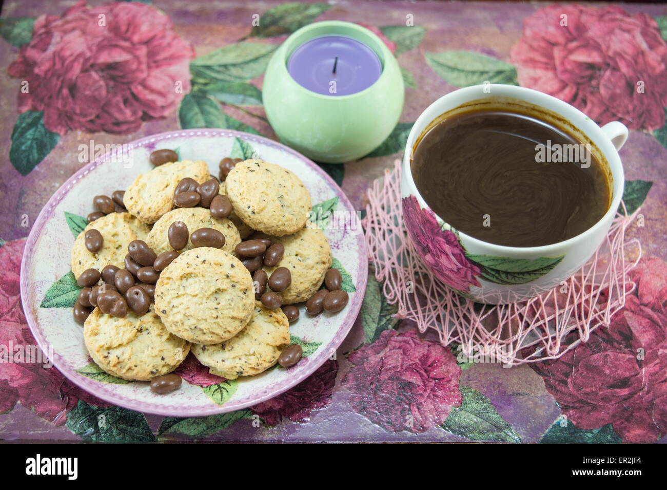 Integrale Cookies und Schokokugeln auf einen bunten Couchtisch mit Blumen Stockfoto