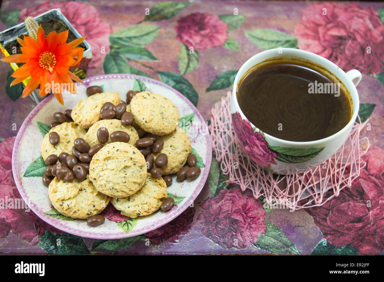 Integrale Cookies und Schokokugeln auf einen bunten Couchtisch mit Blumen Stockfoto