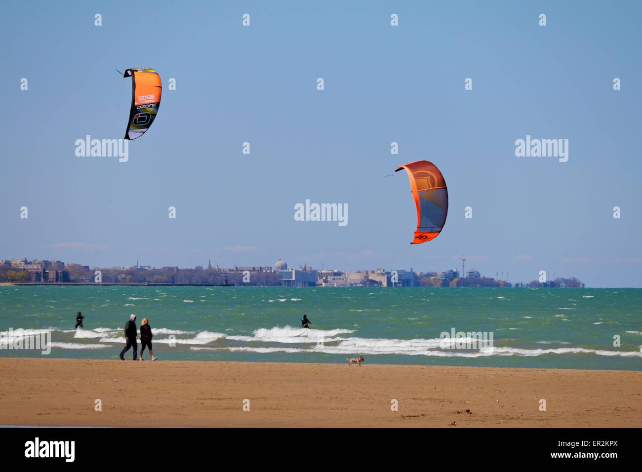 Zwei Kite-Surfer trotzen der Brandung, während ein paar ihren Hund geht. Montrose Strand, Chicago, Illinois Stockfoto