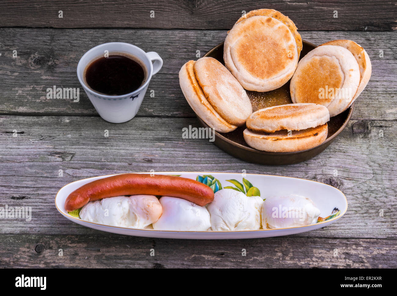 Protein-reichhaltiges Frühstück mit vier Eggs Benedict und Wiener Würstchen mit geröstetem Muffins und eine Tasse Kaffee. Stockfoto