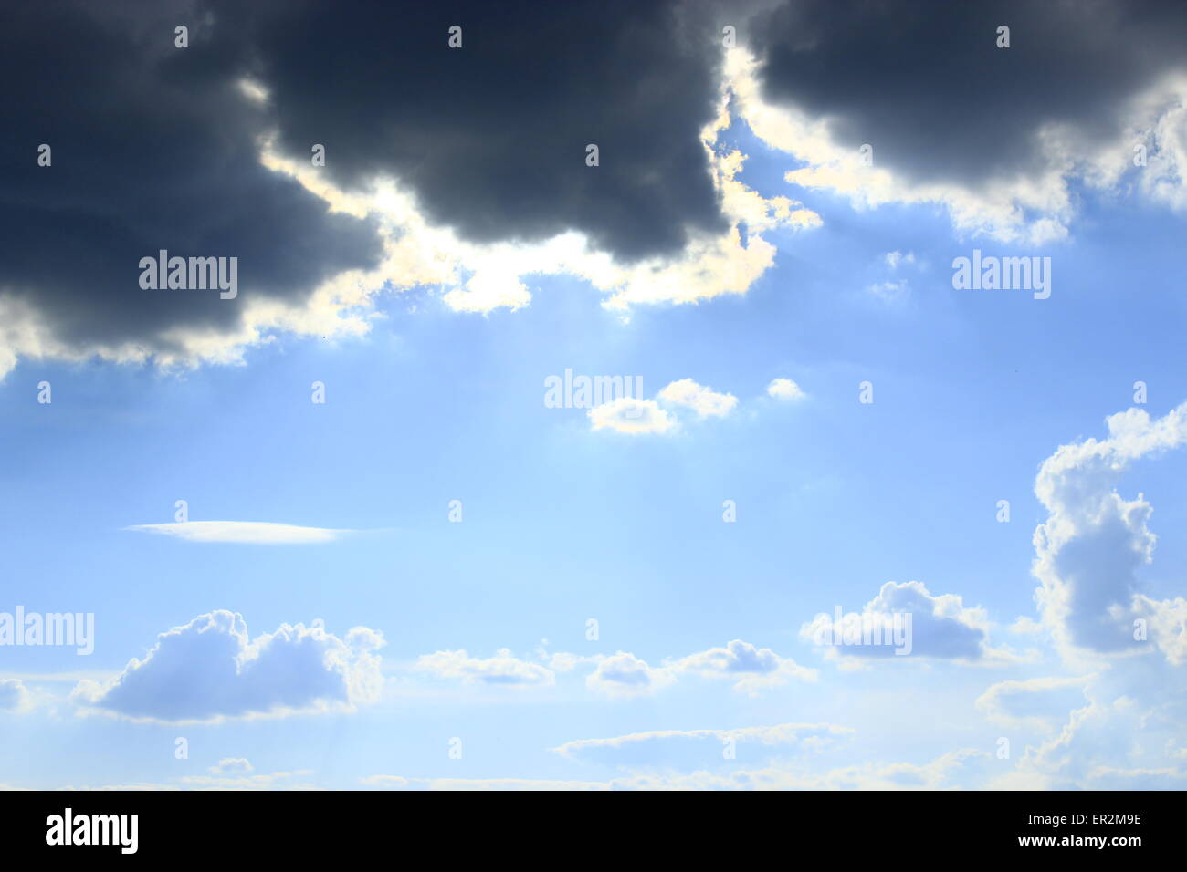 dunkle Wolken am blauen Himmelshintergrund mit Sonnenstrahlen Stockfoto