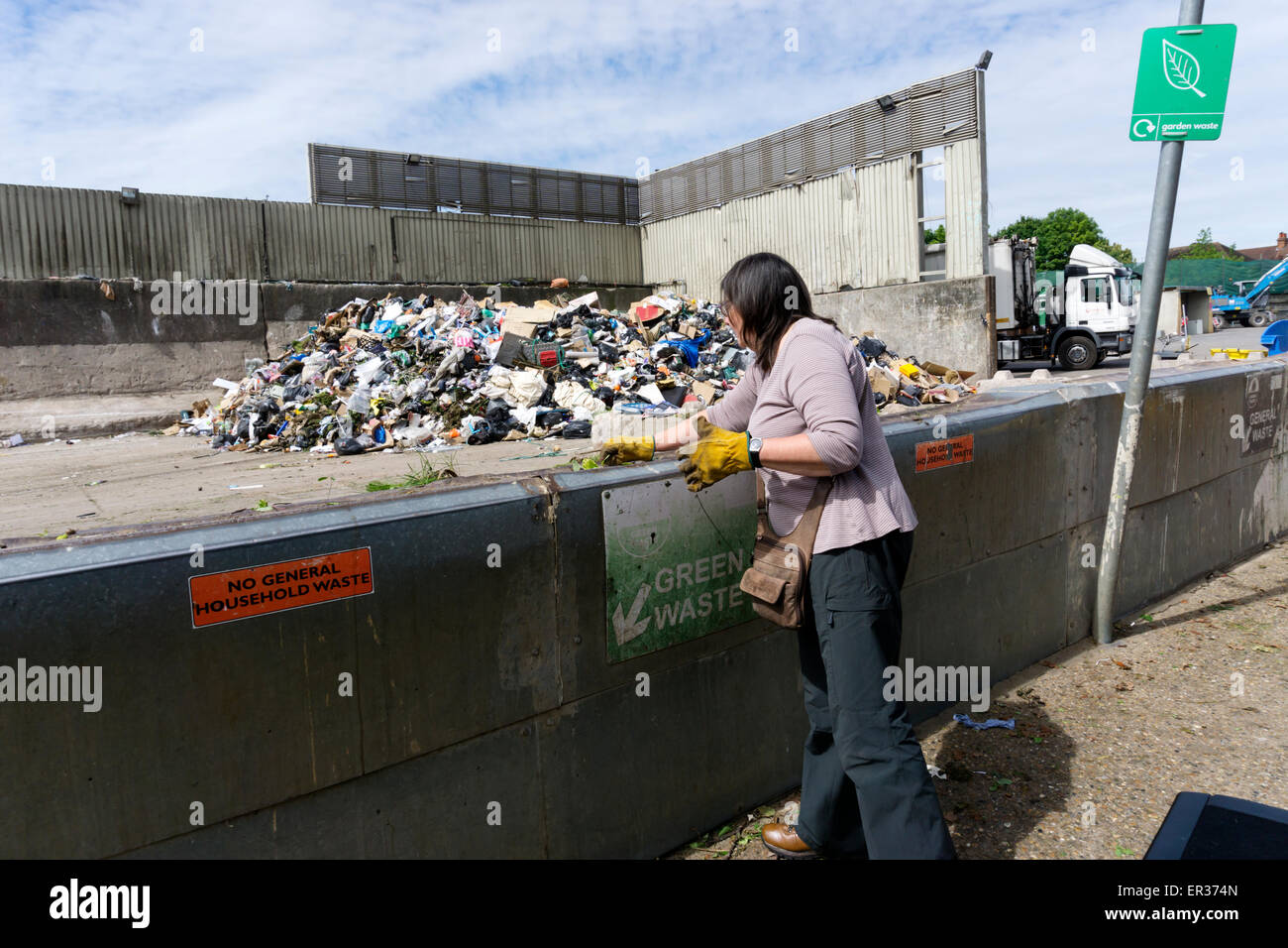 Eine Frau Verklappung von grünen Garten an einem kommunalen Spitze oder Recyclinghof. Stockfoto