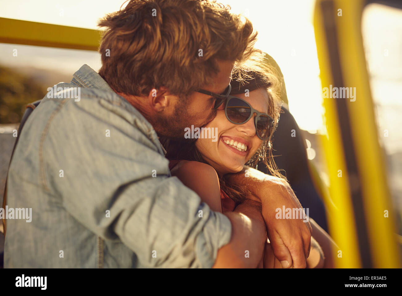 Junger Mann umarmt und küsst seine schöne Freundin während auf einem Roadtrip. Romantisch zu zweit in einem Auto im Sommerurlaub. Stockfoto