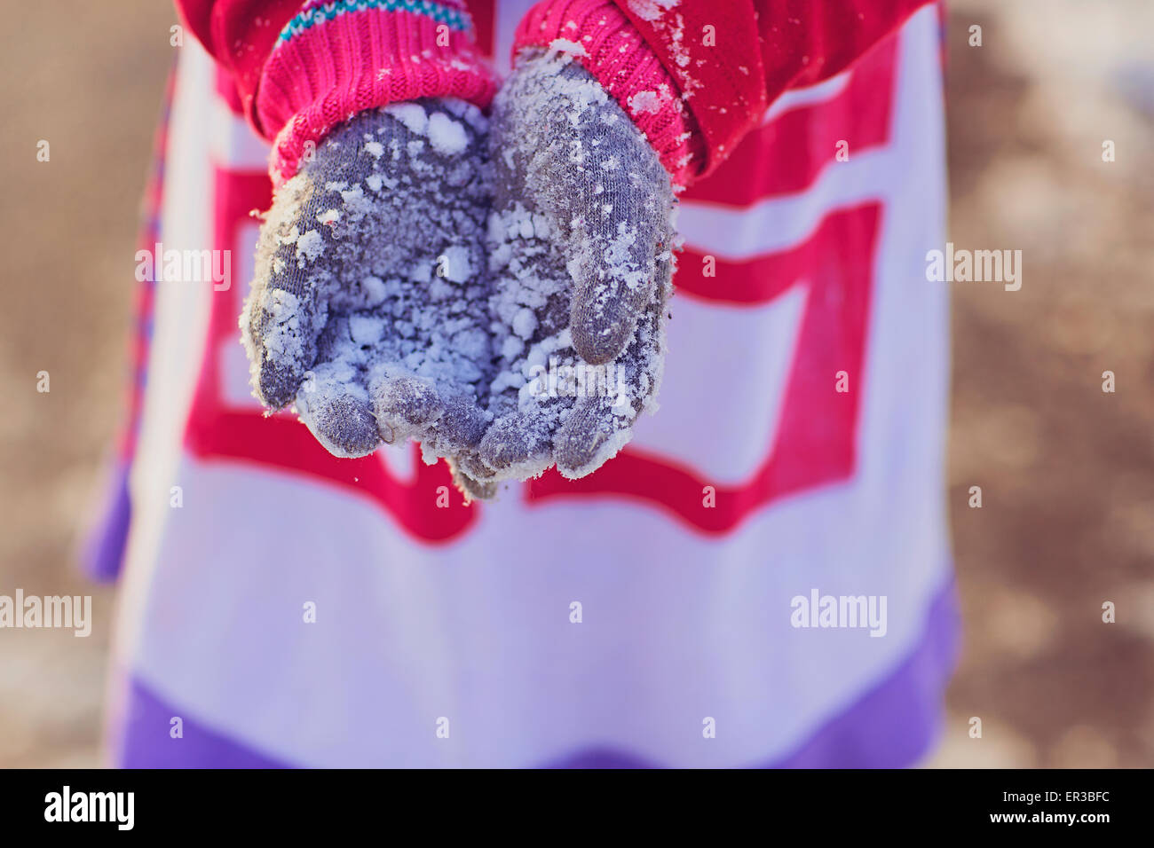 Mädchen hält ihre schneebedeckten Handschuhe Stockfoto
