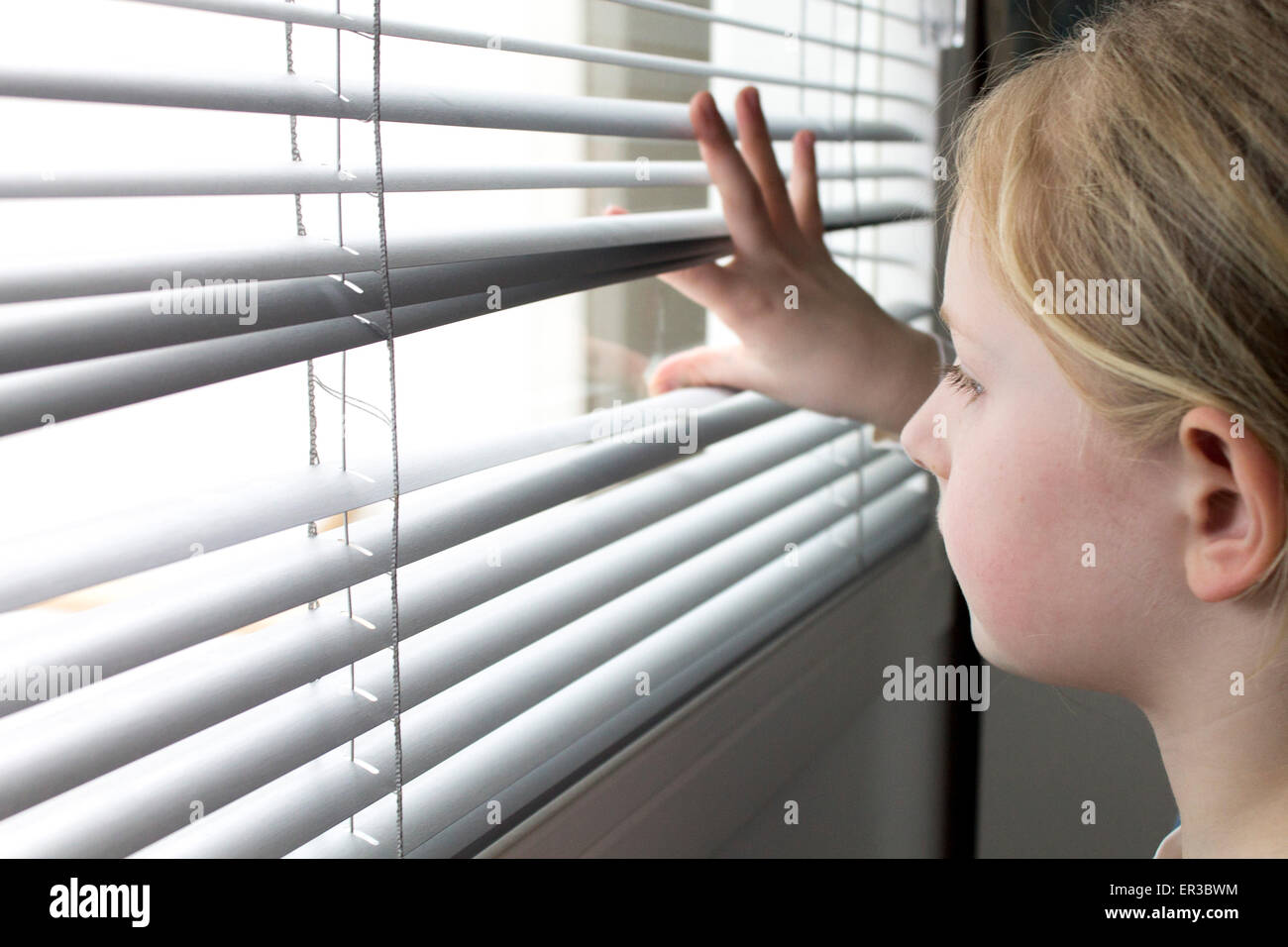 Mädchen auf der Suche durch Fenster-Vorhänge Stockfoto