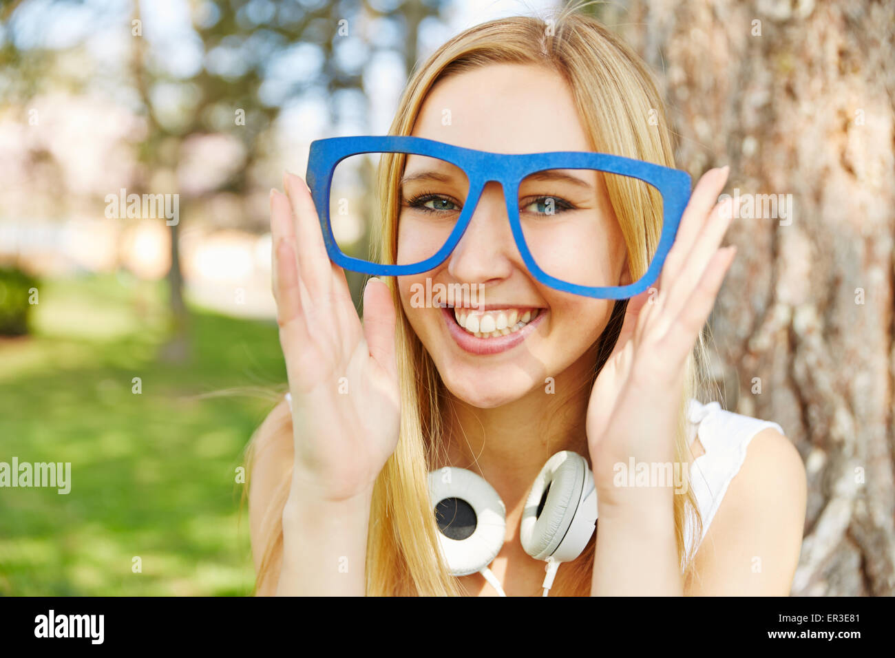 Glückliche junge Frau hält hölzerne Nerd Brille vor ihren Augen im Sommer Stockfoto