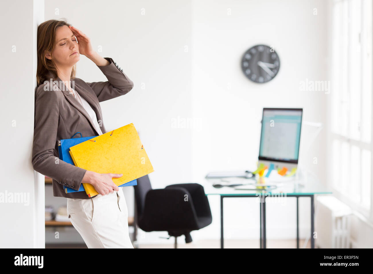 Frau bei der Arbeit, die unter Kopfschmerzen leiden. Stockfoto