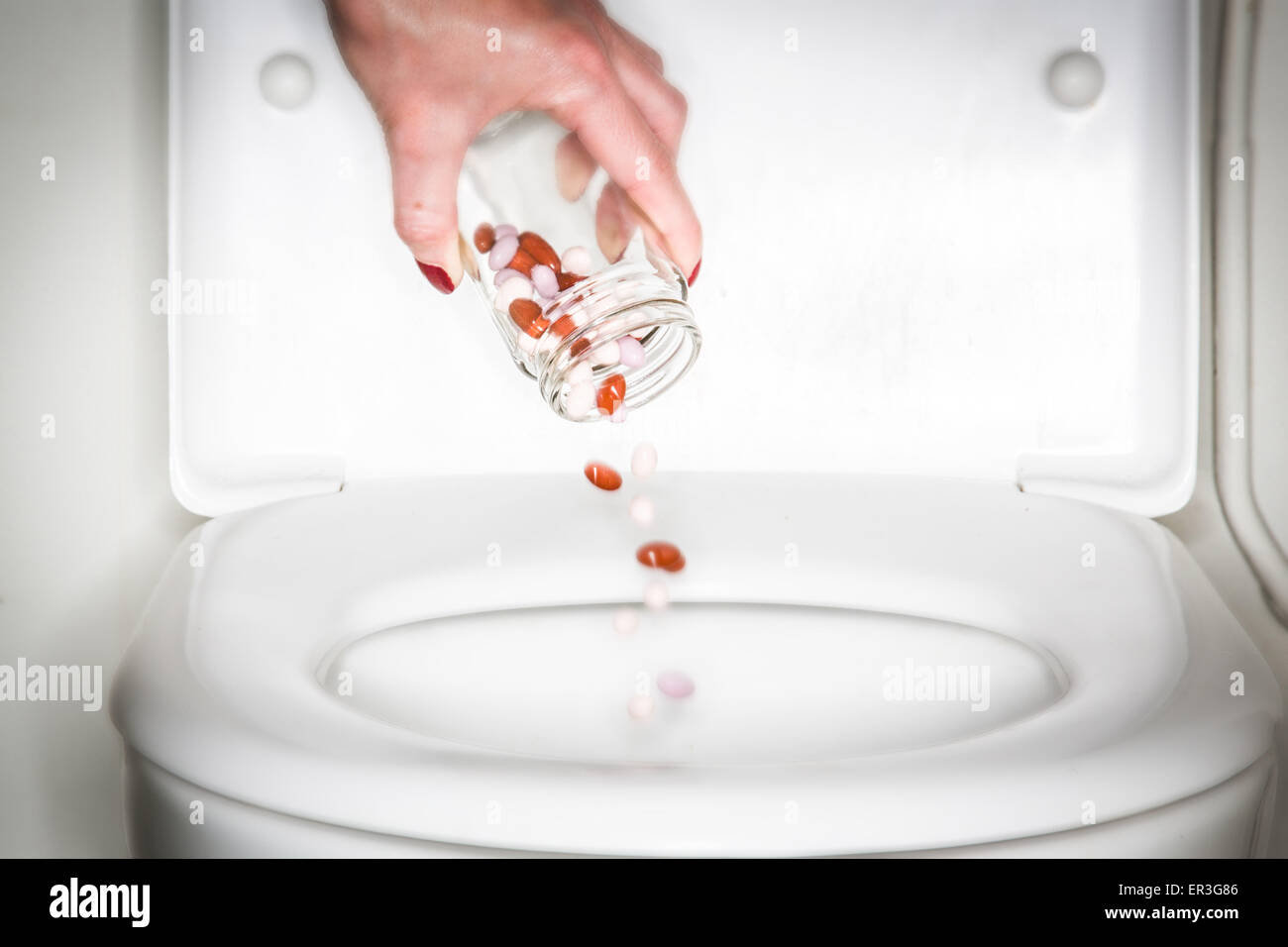 Hand, die Pillen in einer Toilette zu werfen. Stockfoto
