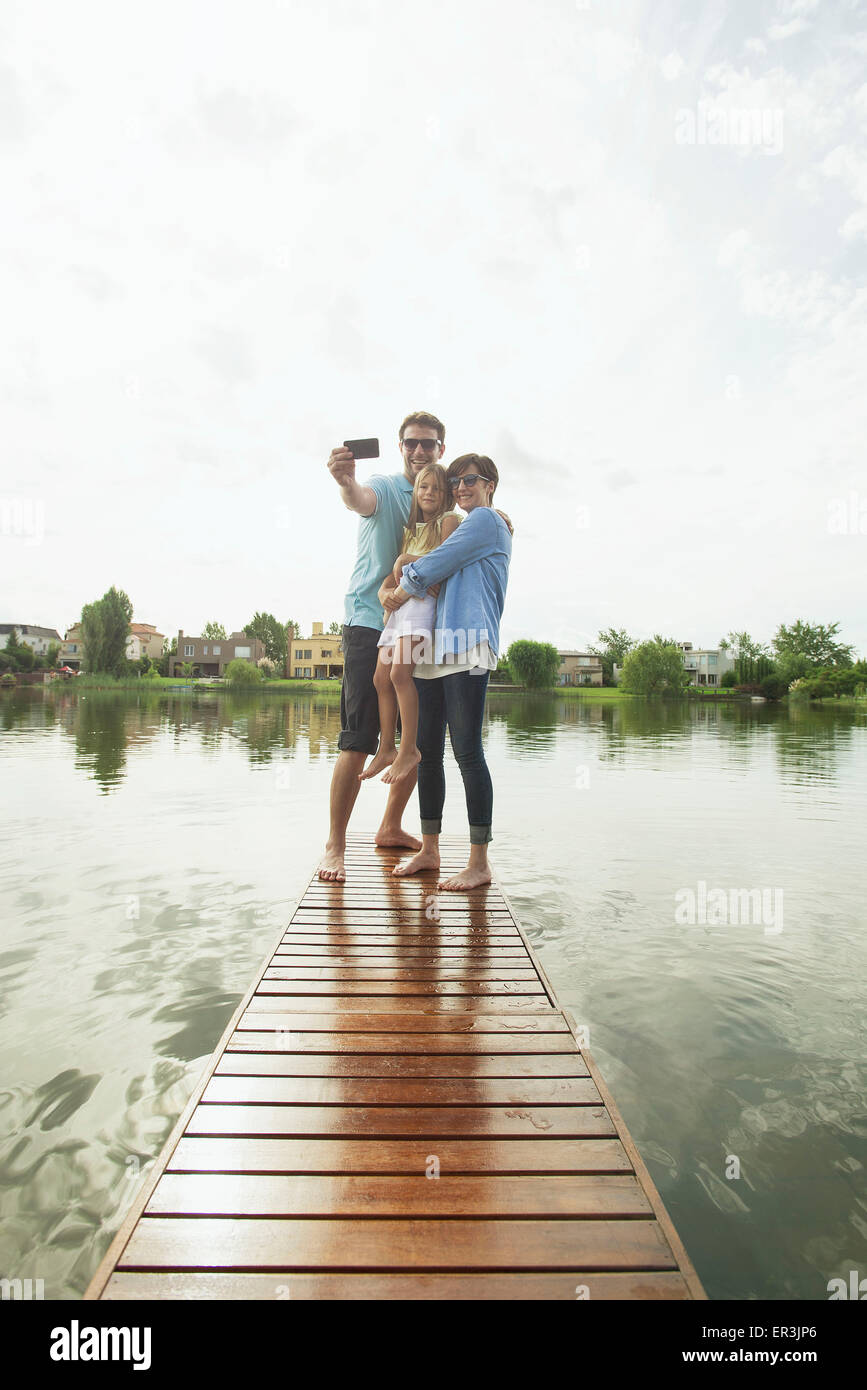Familie mit Tochter am Ende See Pier nehmen Selfie zusammenstehen Stockfoto
