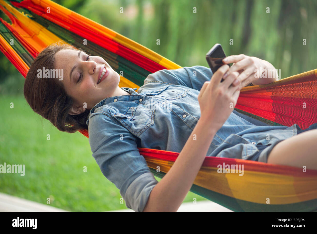 Frau zum Entspannen in der Hängematte mit smartphone Stockfoto