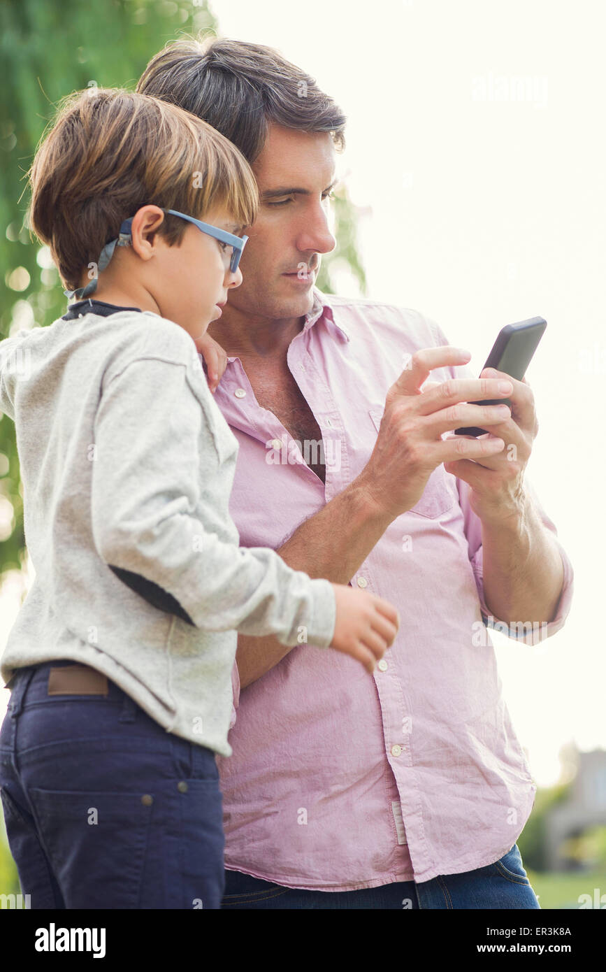 Vater und seinem kleinen Sohn betrachten Smartphone zusammen im freien Stockfoto