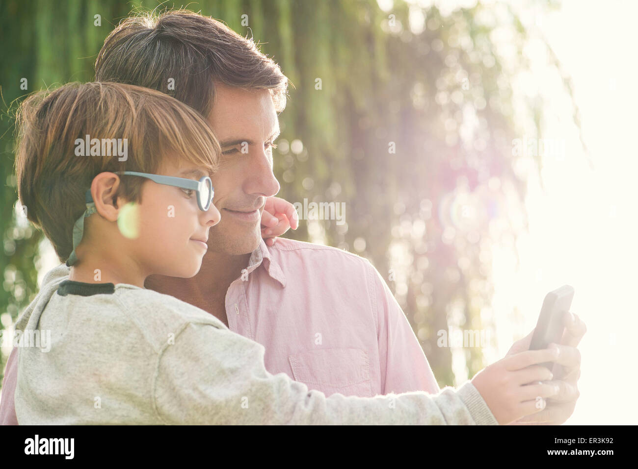 Vater und Sohn posiert für Fotos mit Smartphone, Überbelichtung Stockfoto