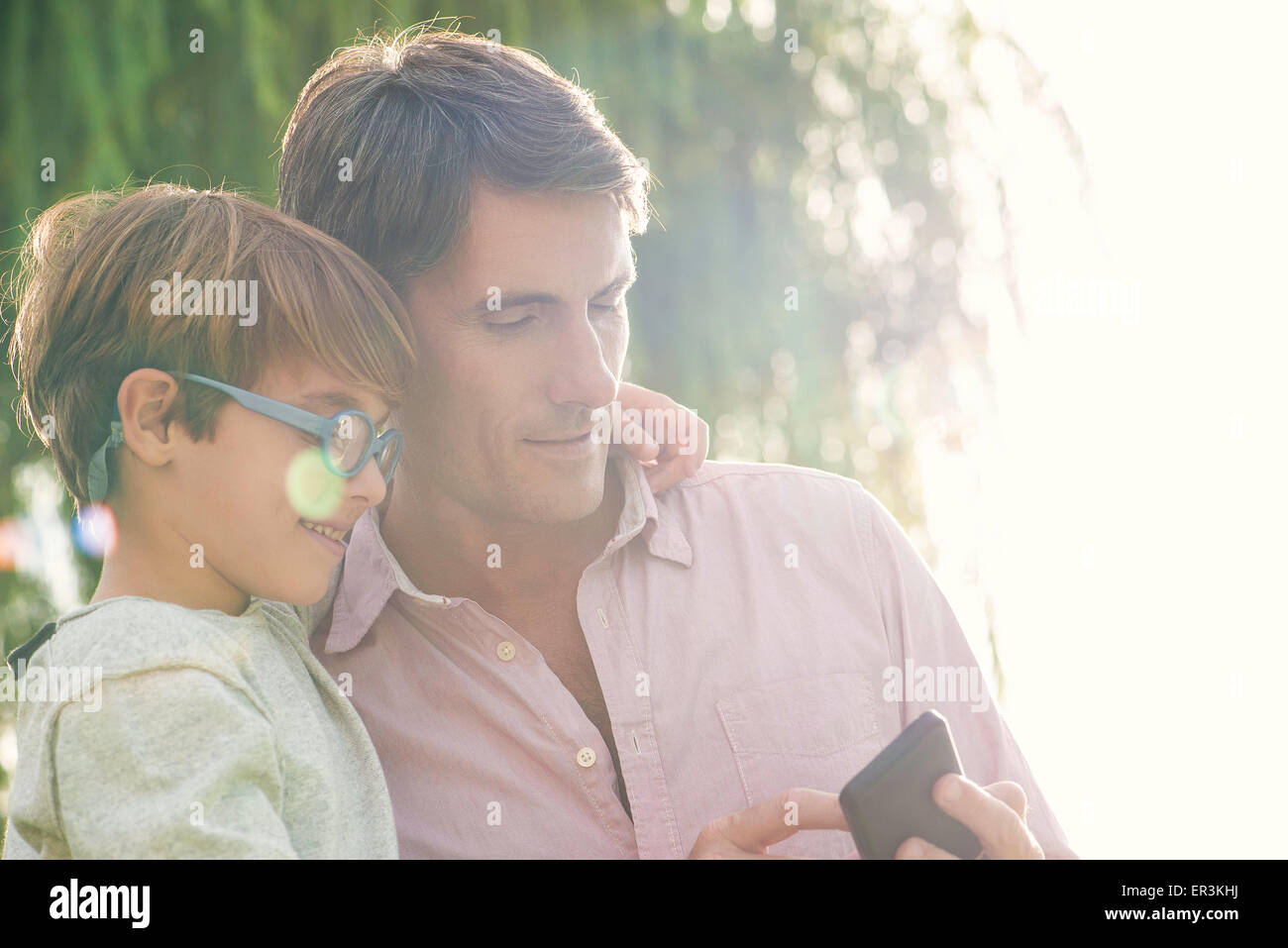 Vater und Sohn betrachten Smartphone im Freien, Überbelichtung Stockfoto