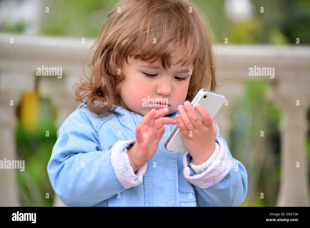 Kleines Mädchen reden über Handy gegen Green Park im Sommer. Stockfoto