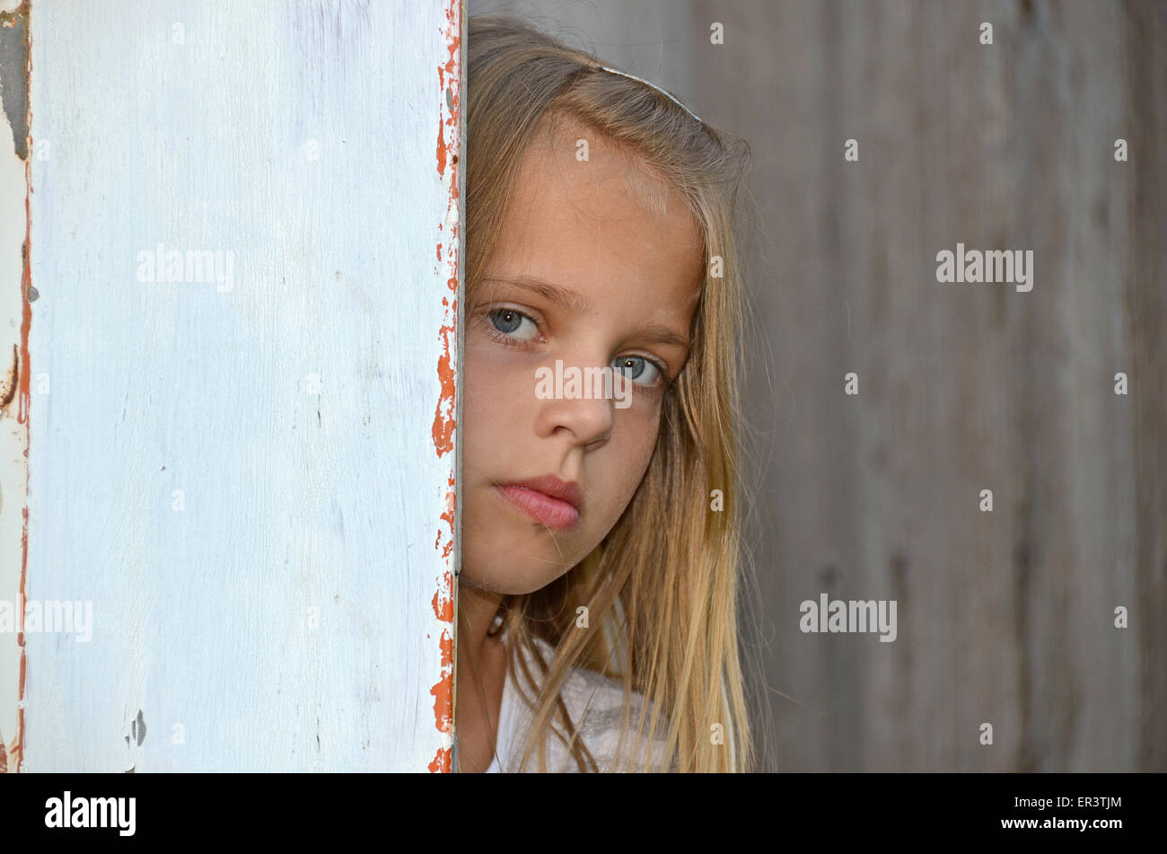 Young Caucasian spähen, um einer alten Holztür. Stockfoto
