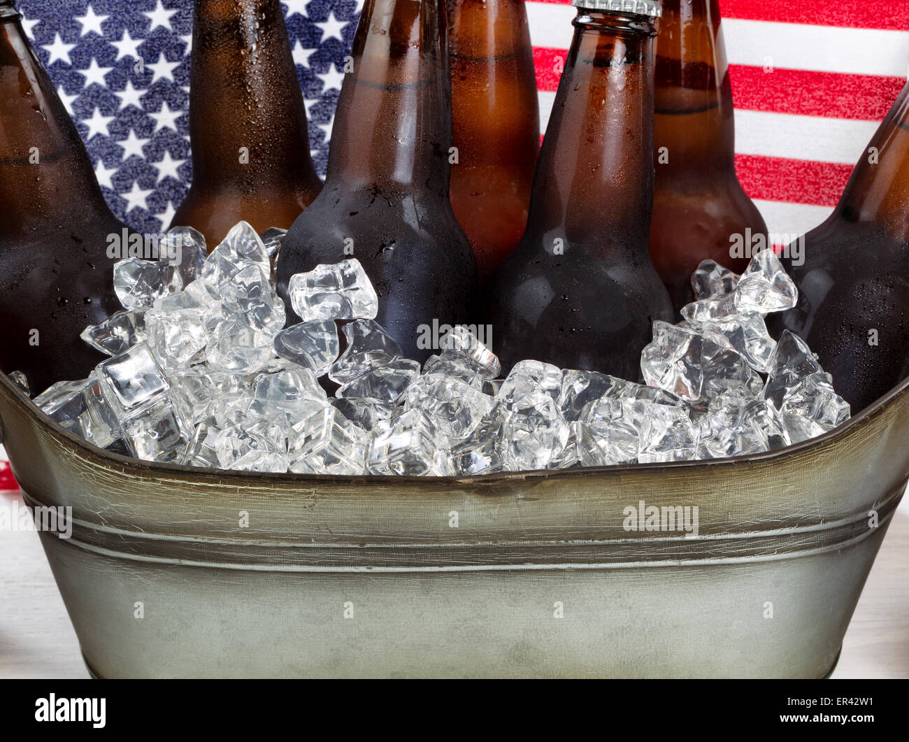 Nahaufnahme, kaltes Bier und Eis in Stahl Wanne mit amerikanischen Flagge im Hintergrund. Fourth Of July Ferienkonzept. Stockfoto