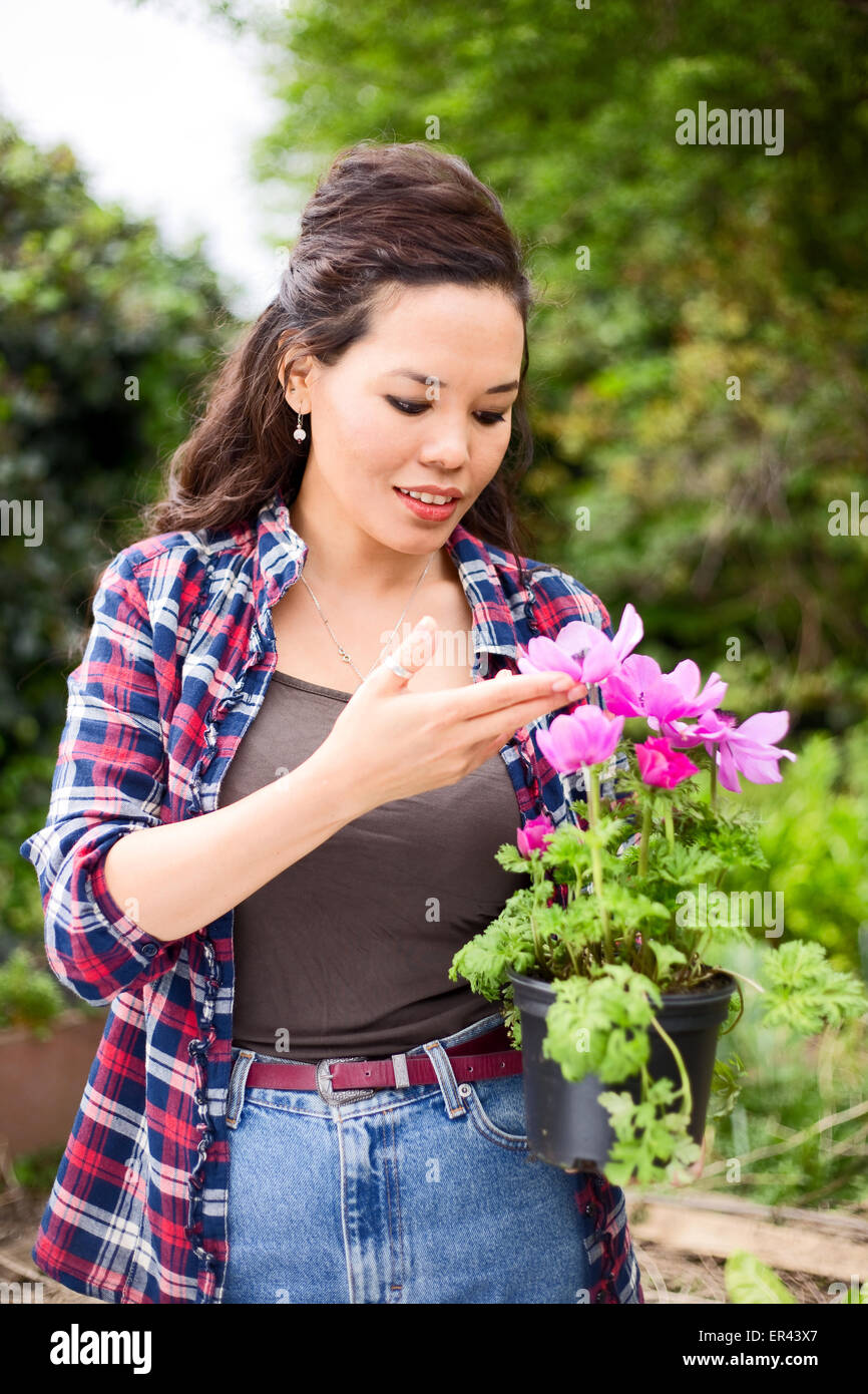 junge Frau hält einen Blumentopf im Garten Stockfoto