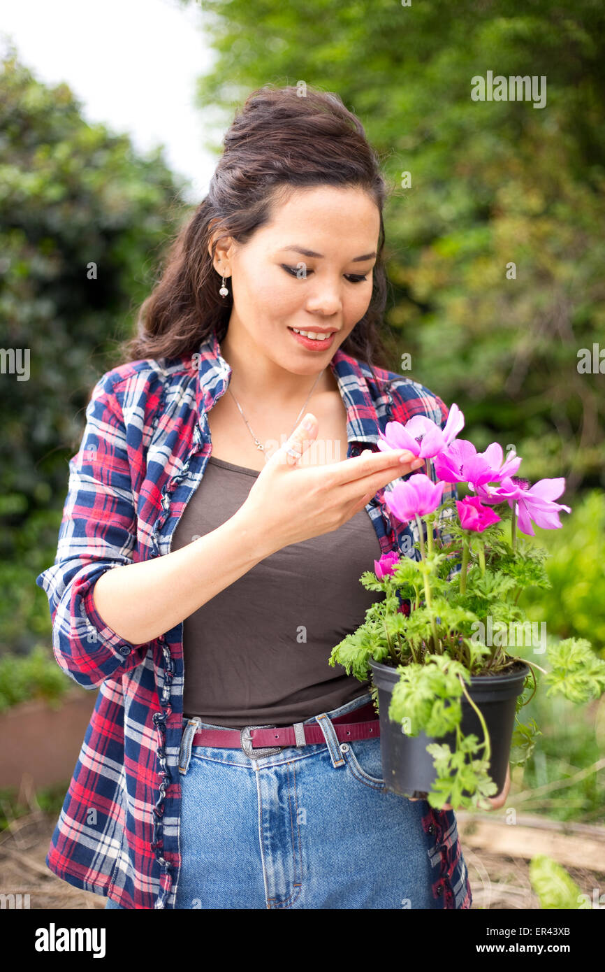 junge Frau hält einen Blumentopf im Garten Stockfoto