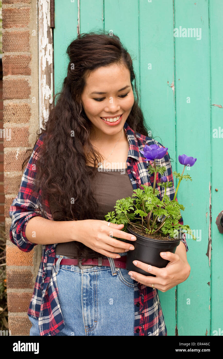 eine junge Frau hält einen Blumentopf im Garten. Stockfoto