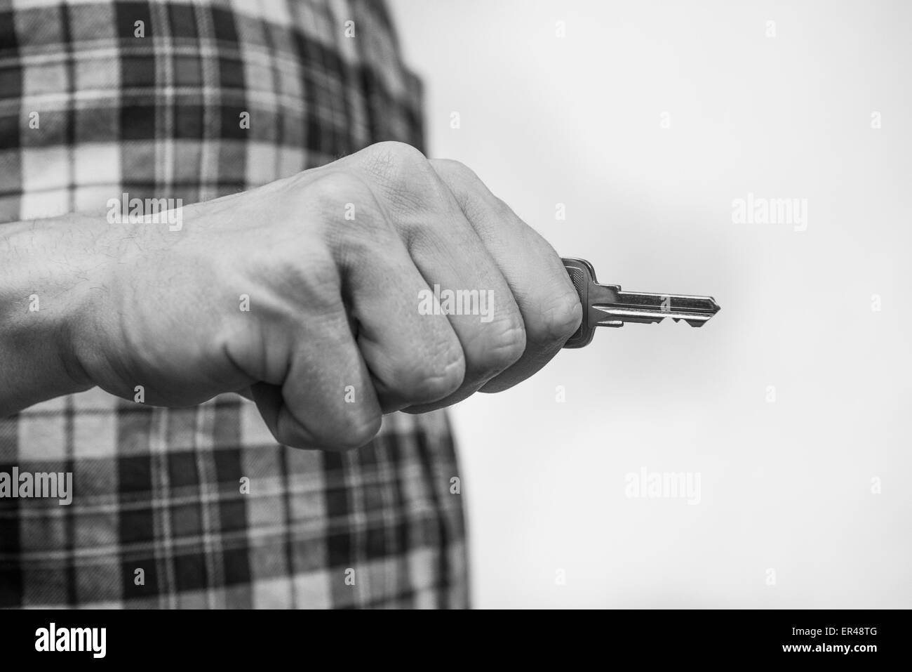 Männliche Hand hält einen silbernen Schlüssel zum Haus. Stockfoto