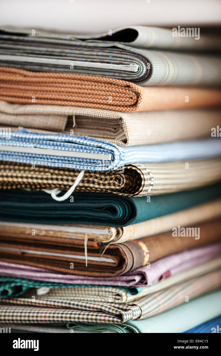Detail der Stapel von gefalteten Stoffen in unterschiedlichsten Farben, Mustern und Texturen im Textilgeschäft hautnah Stockfoto