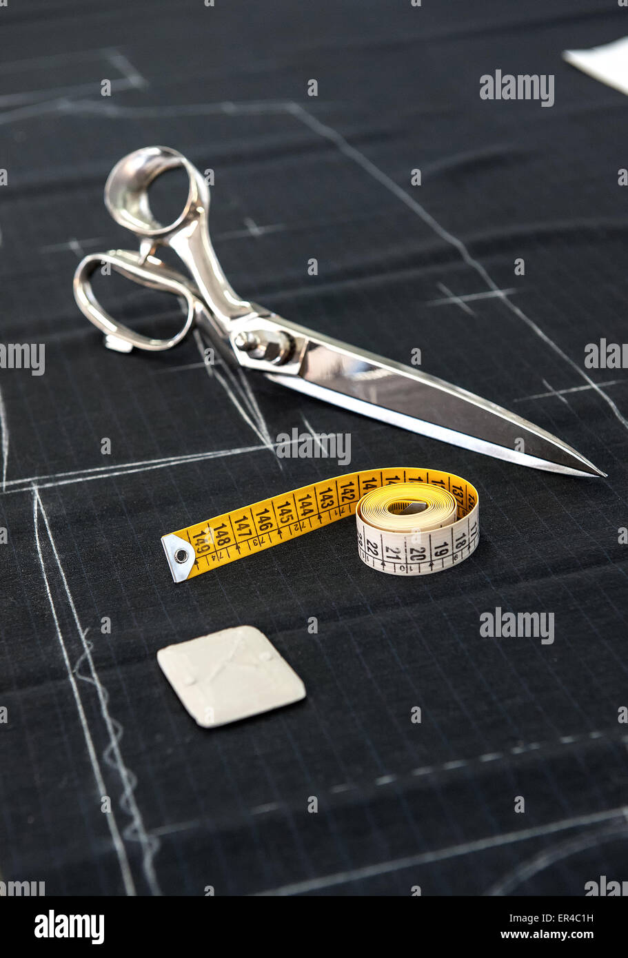 Stillleben mit Stoffschere und Maßband auf Stoff mit Muster in Kleidung Designstudio markiert Stockfoto