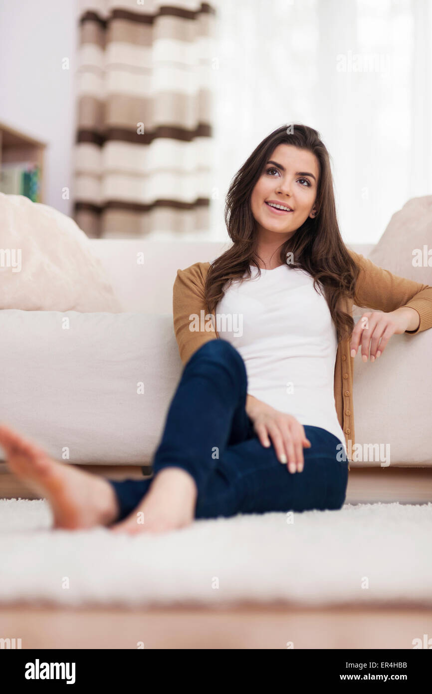 Schöne Frau sitzt vor einem weißen sofa Stockfoto