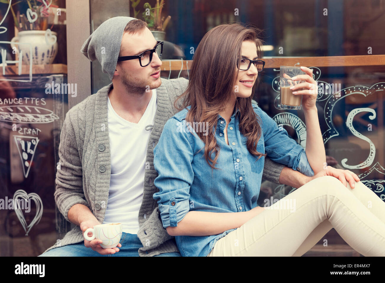 Stilvolle paar mit Tasse Kaffee vor dem Café sitzt. Krakau, Polen Stockfoto