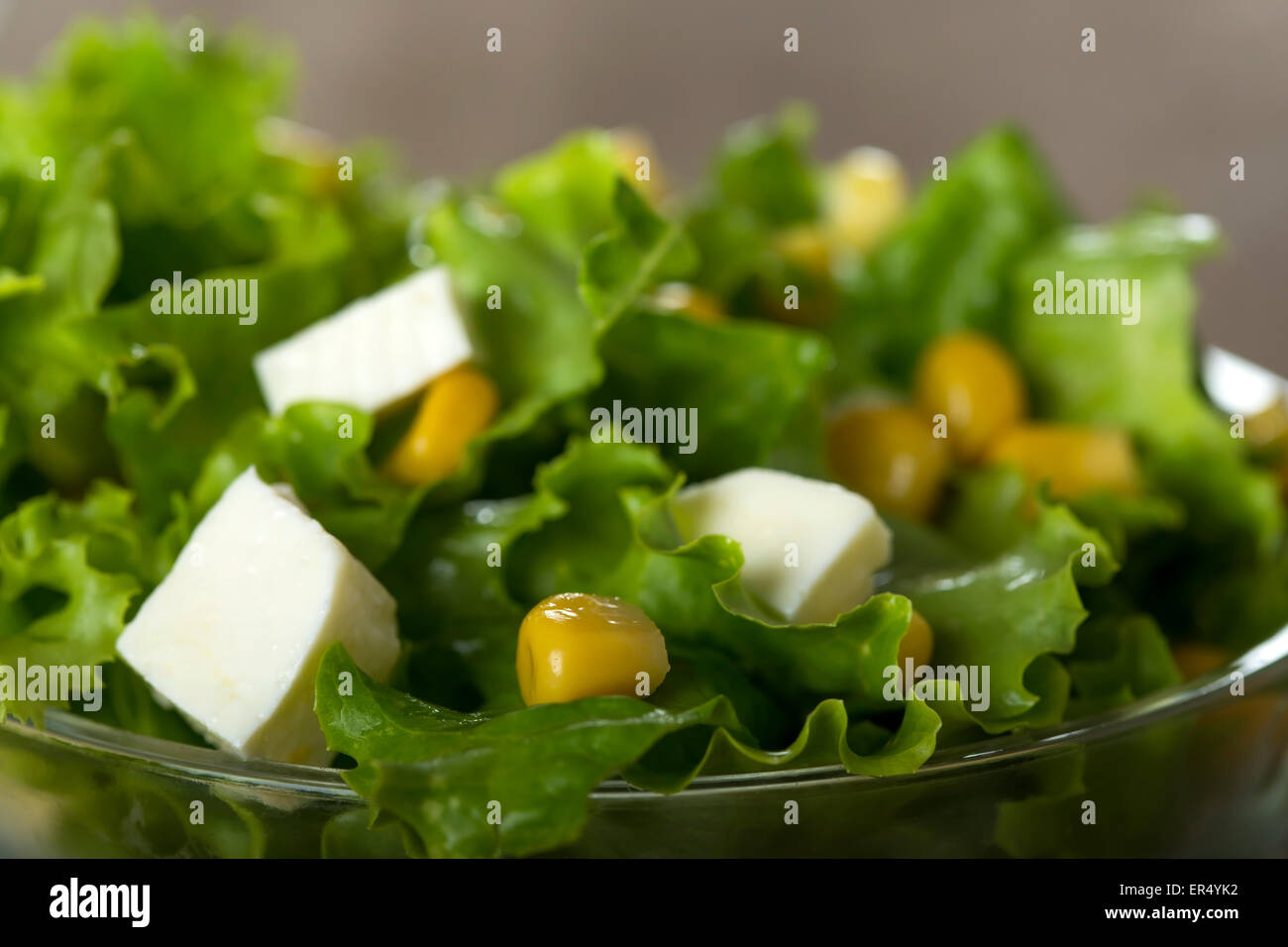 Frischer Salat mit Mais und Käse in Schüssel über Holz Hintergrund Stockfoto