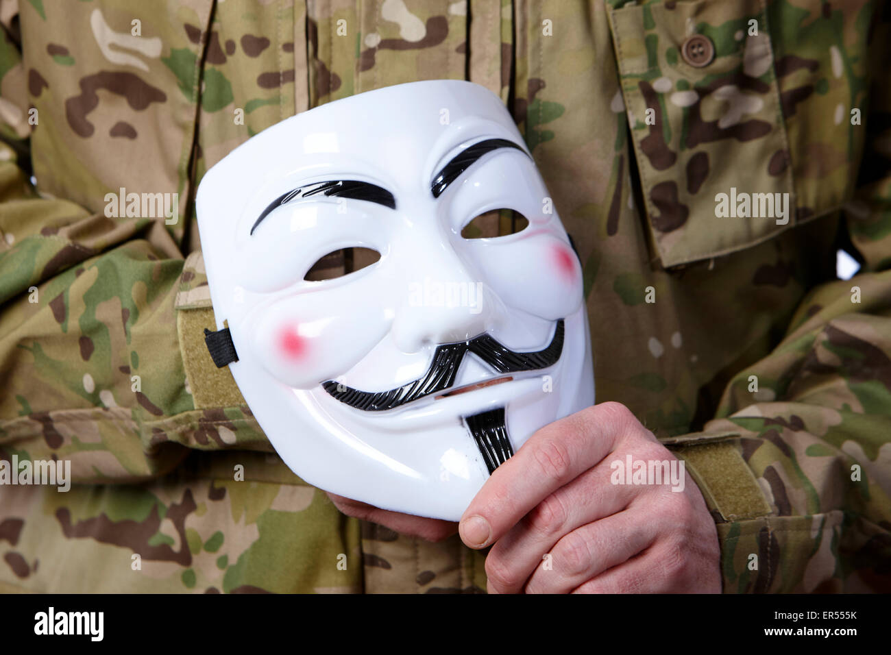 Mann in Kampfuniform mit Kerl Fawkes maskiert durch Hacker-Gruppe anonymous verwendet Stockfoto