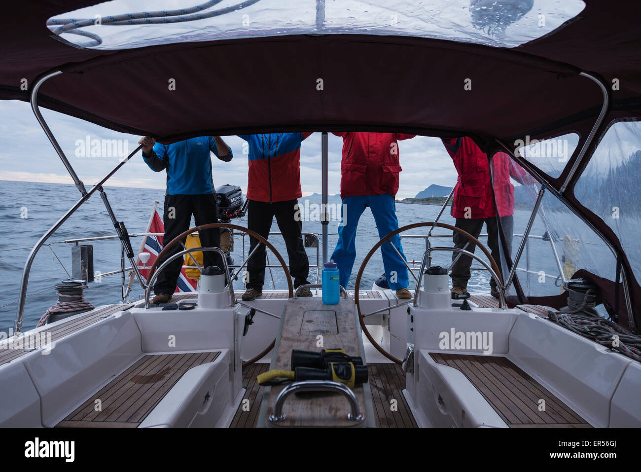 4 Personen in bunte Kleidung auf dem Rücken eines Segelbootes, Lofoten Inseln, Norwegen Stockfoto