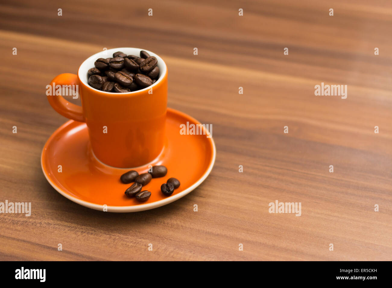 Kaffeebohnen in eine Tasse Espresso auf einem hölzernen strukturierten Hintergrund Stockfoto