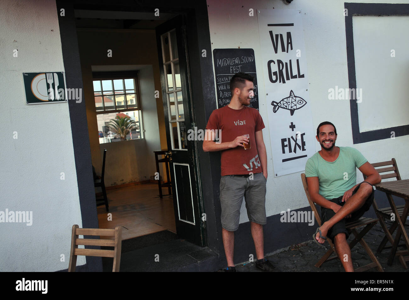 Zwei Männer sitzen vor einer Bar in Madalena, Insel Pico, Azoren, Portugal Stockfoto