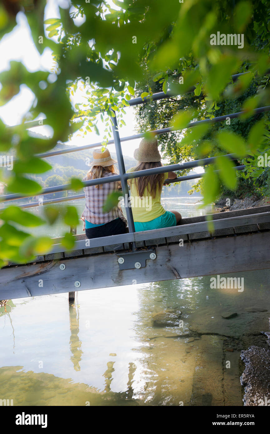Zwei junge Frauen sitzen auf einem Steg am Rhein, Rheinfelden, Baden-Württemberg, Deutschland Stockfoto