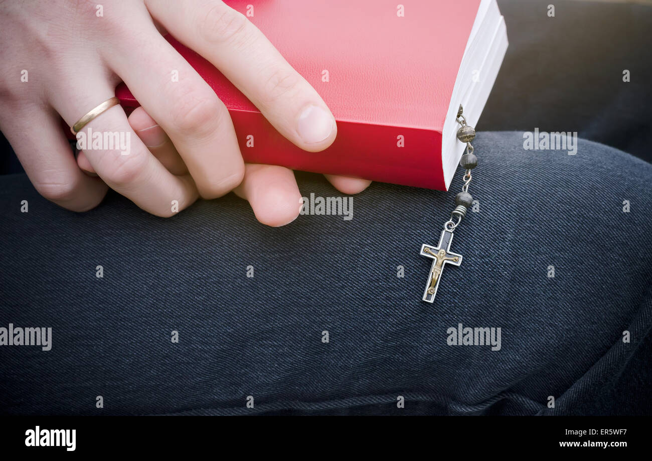 Bibel und Rosenkranz ist in der Hand des Menschen Stockfoto