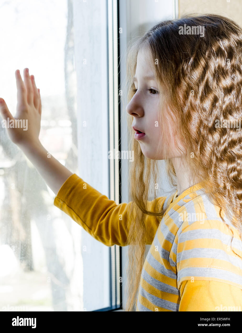 trauriges Kind schaut aus dem Fenster Stockfoto