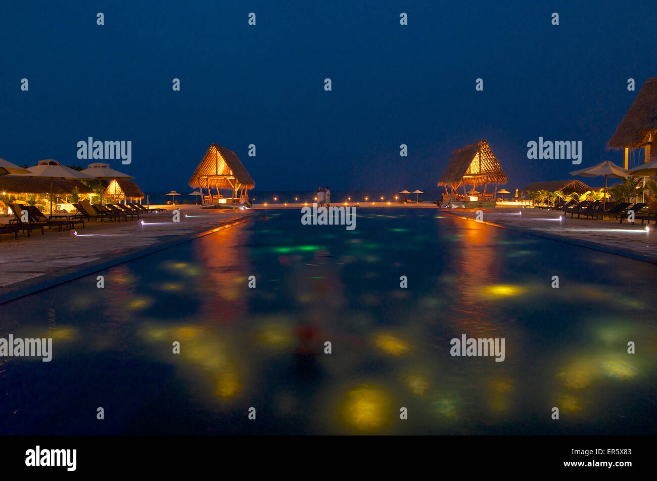 Beleuchteter Pool mit Sonnenliegen am Abend an Maalu Maalu Resort, Passekudah, Ostküste, Sri Lanka Stockfoto
